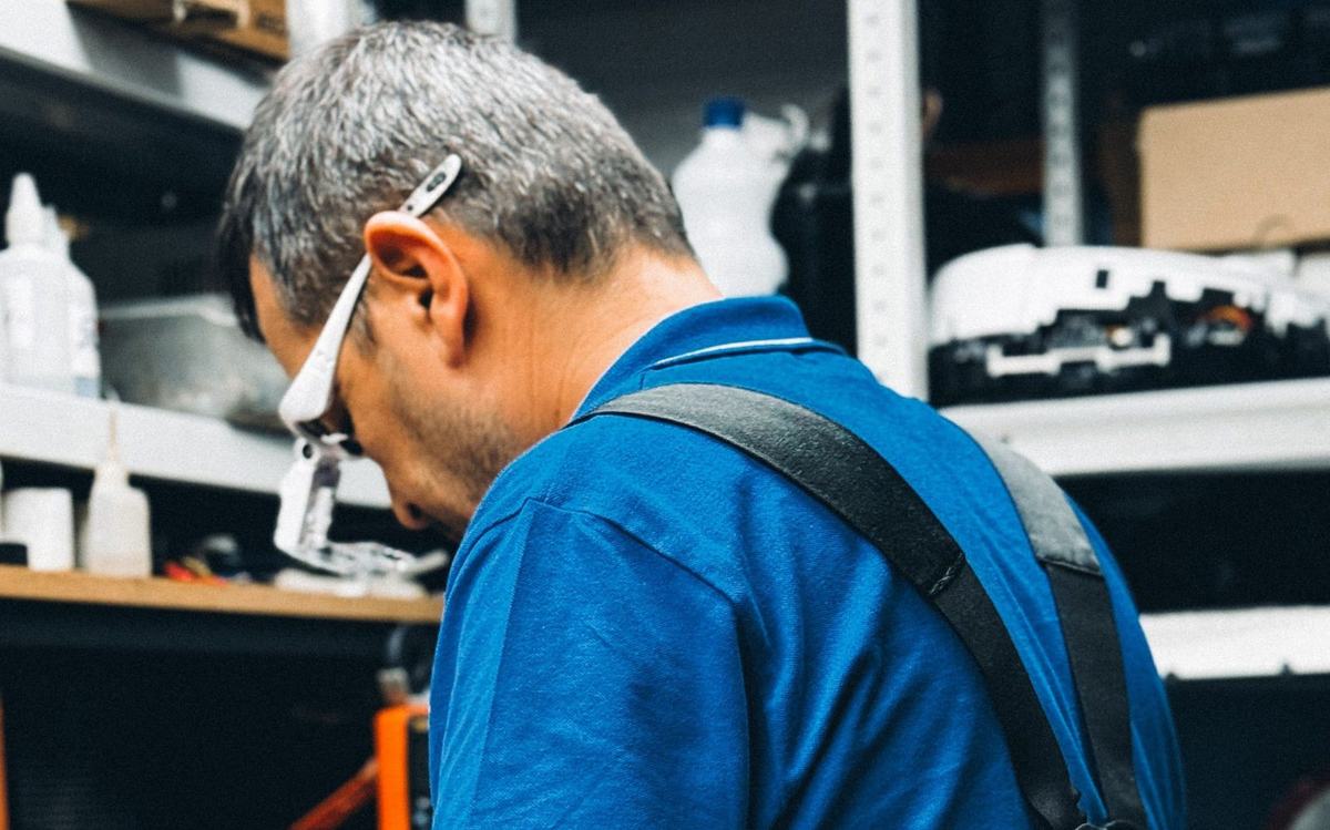 Garage door technician repairing a door mechanism at a workbench